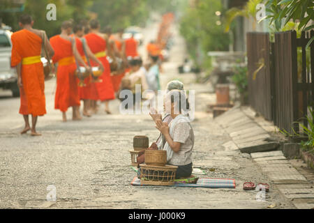 Lao Peoples demokratische Republik Laos, Luang Prabang - 20. Juni 2014: Frau betet nach Almosen zu buddhistische Mönche auf der Straße. Stockfoto