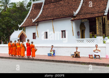 Lao Peoples demokratische Republik Laos, Luang Prabang - 22. Juni 2014: Frau betet nach Almosen zu buddhistische Mönche auf der Straße. Stockfoto