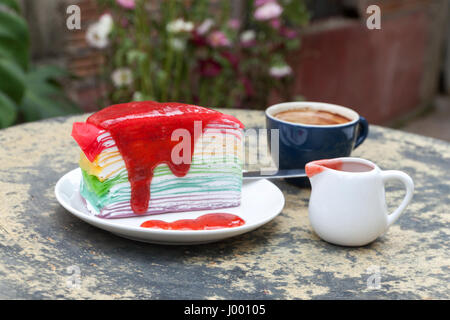 Crêpe Kuchen Rainbow und heißen Espresso-Kaffeemaschine im Gartenseite nach Hause. Krepp-Kuchen mit Erdbeersauce Stockfoto