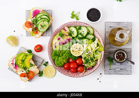 Diät-Menü. Gesunde Lebensweise. Vegane Salat aus frischem Gemüse - Tomaten, Gurke, Wassermelone Rettich und Avocado auf Platte und Sandwiches mit Hersteller Stockfoto