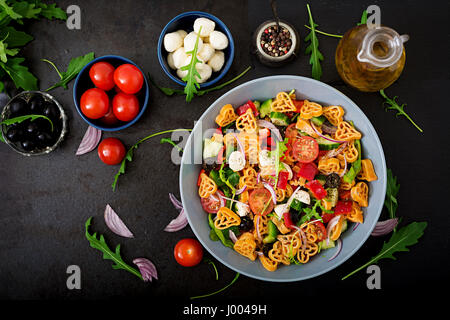 Nudeln in der Form-Herz-Salat mit Tomaten, Gurken, Oliven, Mozzarella und rote Zwiebel griechischen Stil. Flach zu legen. Ansicht von oben Stockfoto