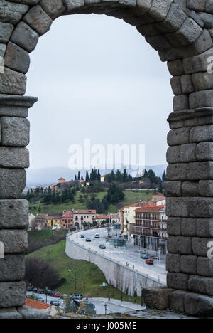 Ein Blick durch den Torbogen des berühmten antiken römischen Aquädukt von Segovia nach Stadt und Straßen, Castilla y León, Spanien. Stockfoto