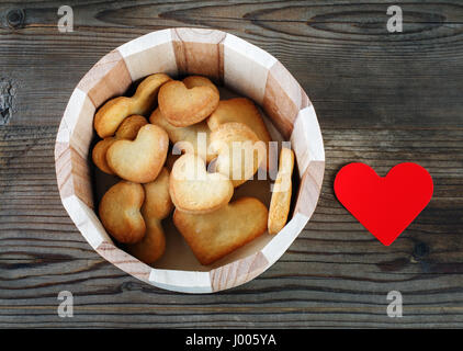 Herzförmige Kekse und rotes Papier Herz auf einem Vintage Holztisch Hintergrund. Stockfoto