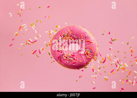 Bestreut rosa Donut. Rosa bereift bestreut Donut auf rosa Hintergrund. Stockfoto