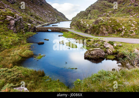 Der Fluss Loe & schmale Straße Bergwind durch das Gap of Dunloe-Tal, eingebettet in die Macgillycuddy riecht nach Bergen der irischen Grafschaft Kerry. Stockfoto