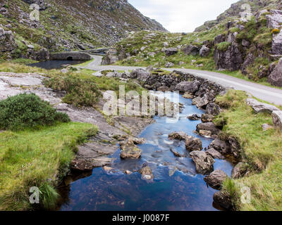 Der Fluss Loe & schmale Straße Bergwind durch das Gap of Dunloe-Tal, eingebettet in die Macgillycuddy riecht nach Bergen der irischen Grafschaft Kerry. Stockfoto