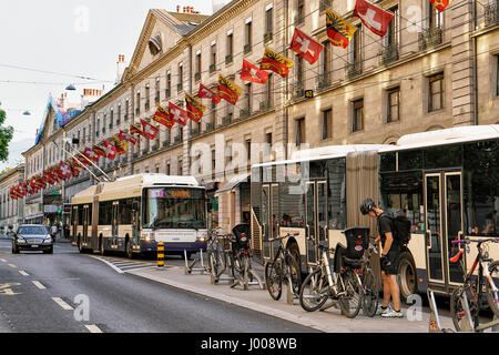 Genf, Schweiz - 30. August 2016: Öffentliche Verkehrsmittel auf an der Rue De La Corraterie Street mit Schweizer Fahnen im Zentrum von Genf, Schweiz. Peop Stockfoto