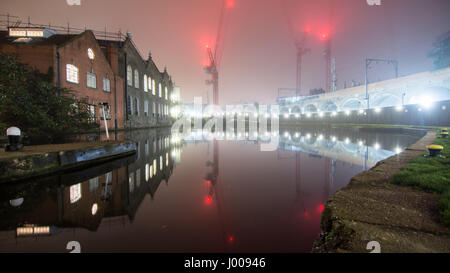 London, England, UK - 30. Dezember 2016: Lagerhallen, Turmdrehkrane und der North London Line Railway die Regents Canal zwischen Kentis spiegeln sich in Stockfoto