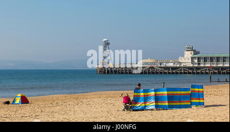 Bournemouth, Dorset, UK. 8. April 2017. UK-Wetter: schönen warmen, sonnigen Tag als Besucher gehen ans Meer machen das Beste aus der Sonne an den Stränden von Bournemouth. Besucher mit Windschutz - Bournemouth Pier in der Ferne. Bildnachweis: Carolyn Jenkins/Alamy Live-Nachrichten Stockfoto