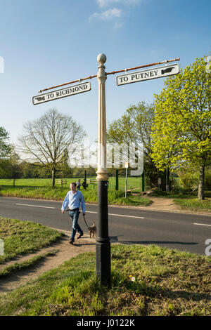 Ein Mann und sein Hund-Pass neben einer alten Finger Straße anmelden Putney Common, Putney, London, UK Stockfoto