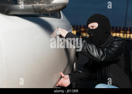 Männliche Dieb mit Haube auf dem Kopf, die Autotür öffnen möchten. Carjacker Fahrzeug entriegeln Stockfoto