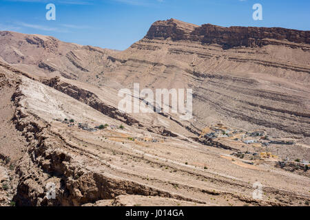 Dorf eingebettet in die trockenen Berge von Wadi Bani Khalid, Sultanat von Oman, traditionelle Architektur und zerklüftete Wüstenlandschaft, heißes Klima Stockfoto