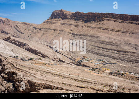 Dorf eingebettet in die trockenen Berge von Wadi Bani Khalid, Sultanat von Oman, traditionelle Architektur und zerklüftete Wüstenlandschaft, heißes Klima Stockfoto