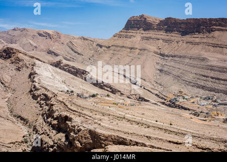 Dorf eingebettet in die trockenen Berge von Wadi Bani Khalid, Sultanat von Oman, traditionelle Architektur und zerklüftete Wüstenlandschaft, heißes Klima Stockfoto