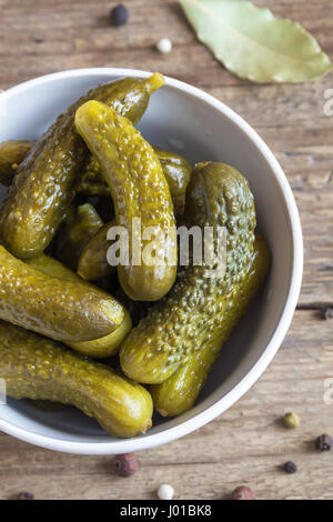 Eingelegtes Gemüse. Schüssel mit Essiggurken (Gurken) über rustikalen hölzernen Hintergrund hautnah. Stockfoto