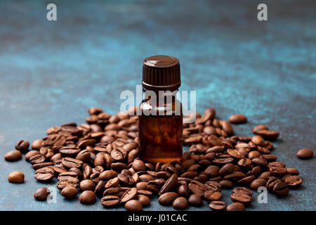 Kaffee ätherisches Öl in einer Glasflasche, Kaffeebohnen auf blauem Hintergrund Stockfoto