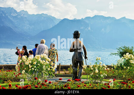 Vevey, Schweiz - 27. August 2016: Menschen an Charlie Chaplin-Statue am Genfersee in Vevey, Kanton Waadt in der Schweiz. Alpen Berge auf der Rückseite Stockfoto