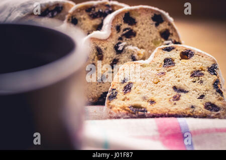 Christstollen, traditionelle deutsche Weihnachten Hefekuchen mit Rosinen, serviert mit einer Tasse Kaffee, dekoriert mit Tischdecke auf Holztisch, selektiven Fokus Stockfoto