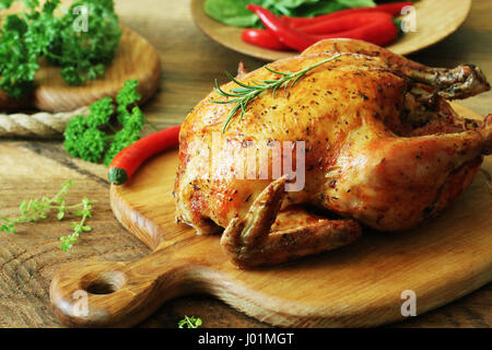 Ganz gebratenes Huhn auf Schneidebrett Stockfoto