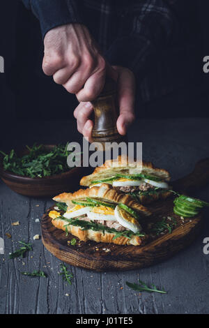 Hände, die Sandwiches mit Thunfischsalat würzen. Tiefenschärfe, getönten Bild Stockfoto