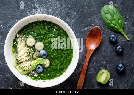 Grüne Spinat und Grünkohl Smoothie mit Chia-Samen, Kiwi und Blaubeeren auf Schiefer Hintergrund. Ansicht von oben, Nahaufnahme Stockfoto