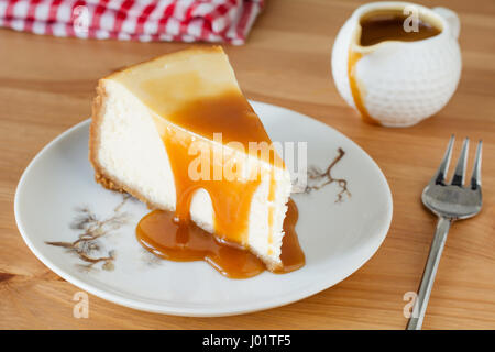 Käsekuchen mit Karamell-Sauce auf einem Teller über Holztisch Hintergrund Stockfoto