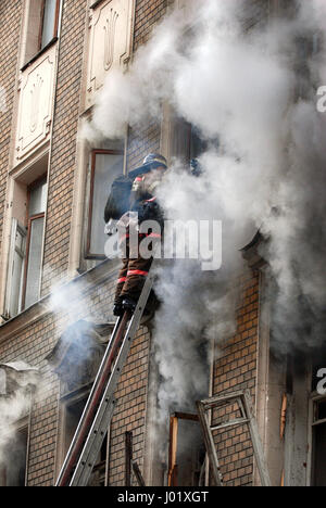 Feuerwehrmann löscht einen Brand in einem Mehrfamilienhaus Stockfoto