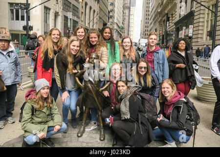 Touristen posiert mit furchtlosen Mädchen Statue starrte die Aufladung Wall Street Bull, NYC, USA Stockfoto