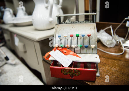 Sehr beliebte alte Metall Vintage Kinder Spielzeug Kasse zum Verkauf in einem Antiquitätengeschäft mit farbigen Tabs und eine rote Kassenschublade. Stockfoto