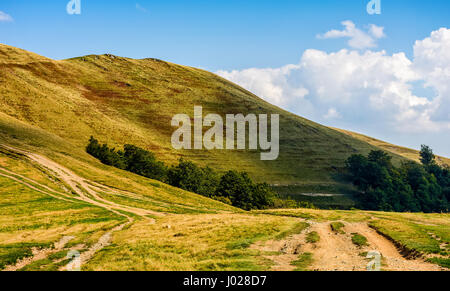 gewundenen Weg durch große Wiesen am Hang. Auf der Spur bergauf Karpaten Bergrücken. warmen und sonnigen Herbsttag mit bewölktem Himmel. Stockfoto