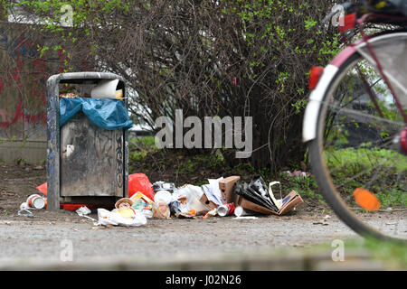 Berlin, Deutschland. 3. April 2017. Ein Radfahrer Fahrräder vorbei eine überlaufende Abfalleimer in einem Park im Stadtteil Kreuzberg in Berlin, Deutschland, 3. April 2017. Müll ist in Grünflächen der Stadt im Zuge der warmes Wetter und Sonnenschein aufgestapelt. Foto: Paul Zinken/Dpa/Alamy Live News Stockfoto