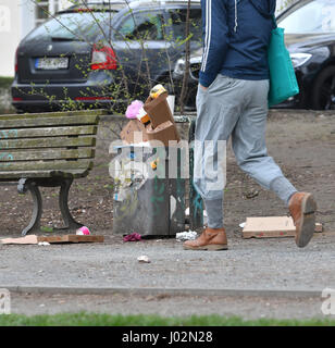 Berlin, Deutschland. 3. April 2017. Ein Mann geht vorbei an einer überquellenden Mülltonne in einem Park im Stadtteil Kreuzberg in Berlin, Deutschland, 3. April 2017. Müll ist in Grünflächen der Stadt im Zuge der warmes Wetter und Sonnenschein aufgestapelt. Foto: Paul Zinken/Dpa/Alamy Live News Stockfoto