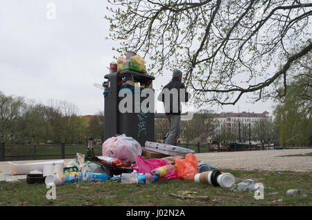 Berlin, Deutschland. 3. April 2017. Ein Mann joggt vorbei eine überlaufende Abfalleimer in einem Park im Stadtteil Kreuzberg in Berlin, Deutschland, 3. April 2017. Müll ist in Grünflächen der Stadt im Zuge der warmes Wetter und Sonnenschein aufgestapelt. Foto: Paul Zinken/Dpa/Alamy Live News Stockfoto