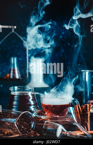 Dunkle Essen Foto mit dampfenden Tasse Kaffee, Zimt, Labor-Trichter, Becher und Reagenzgläser