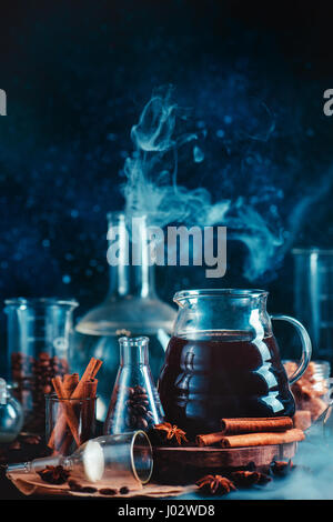 Wissenschaftliche Stillleben mit Kaffee-Topf, Tassen, Gewürze, Anis, Zimt und Labor-Glaswaren auf dunklem Hintergrund Stockfoto