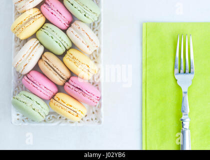 Candy farbigen Makronen-Kuchen mit einer Silber Gabel auf einer Serviette lindgrün, hell und bunt mit textfreiraum ideal für Text links des Menüs "süß" Stockfoto