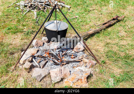 Kochen über dem offenen Feuer auf dem Campingplatz im sonnigen Sommertag Stockfoto