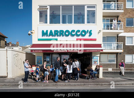 Menschen in einer Warteschlange außerhalb der berühmten Morroco italienischen Restaurant und Eis Eisdiele direkt am Meer in Hove, UK Stockfoto