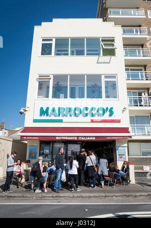 Menschen in einer Warteschlange außerhalb der berühmten Morroco italienischen Restaurant und Eis Eisdiele direkt am Meer in Hove, UK Stockfoto