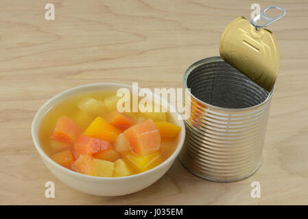 Tropische Früchte-Mischung aus Ananas und Papaya in weißer Schale und geöffnete Dose Dosen Stockfoto