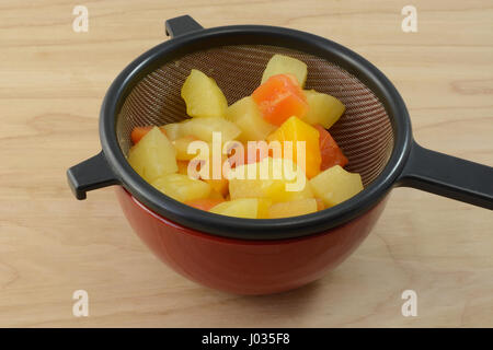 Tropische Früchte-Mischung aus Ananas und Papaya in Sieb abtropfen in Dosen Stockfoto