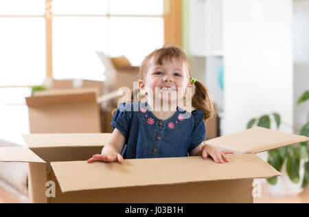 Lachende Mädchen sitzen im inneren Karton Boxe in ihrem neuen Zuhause Stockfoto