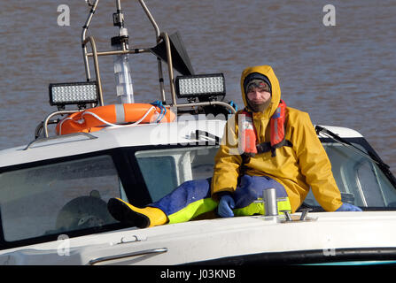 Fischereifahrzeug mit Crew-Mitglied auf Bogen sitzend zurück. Stockfoto