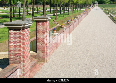 Steinmauer mit Veilchen dekoriert gefüllten Tontöpfen im niederländischen Barock von The Loo Gartenpalais. Stockfoto