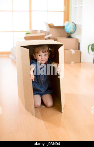 Glückliches Kind spielen mit Kisten nach dem Umzug in neues Haus Stockfoto