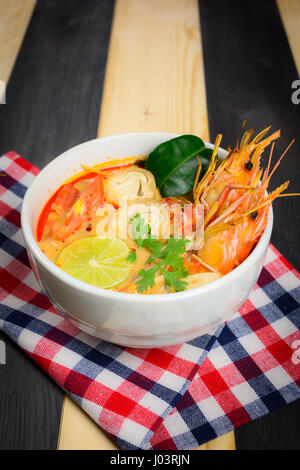 Tom Yum Soup oder Fluss Garnelen scharf saure Suppe (Tom Yum Goong) auf Holztisch mit Tischdecke, thailändische Spezialitäten Stockfoto