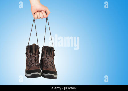 Neue Schuhe in der Hand auf blauem Hintergrund. Hand halten Schuhe Schnürsenkel. Verkauf-Hintergrund mit Exemplar auf blauem Hintergrund. Stockfoto