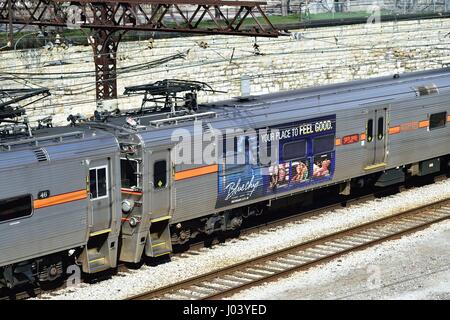 Ein South Shore Line Pendlerzug sporting Werbung ankommen auf Spuren des Chicago Millennium Park entfernt. Chicago, Illinois, USA. Stockfoto