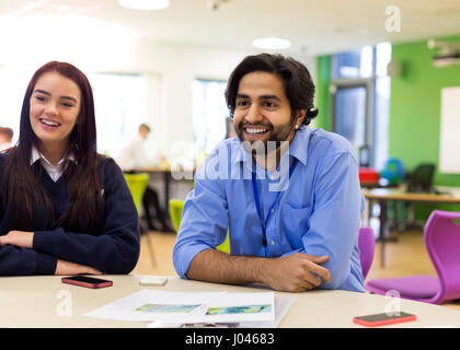 Lehrer im Gespräch mit einer Gruppe von Studenten an einem Tisch in einem Klassenzimmer. Stockfoto