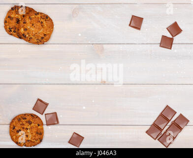 Stücke von Schokolade und Haferflocken Cookies mit Schokolade verteilen sich auf einem Holztisch. Es gibt einen Platz für text Stockfoto